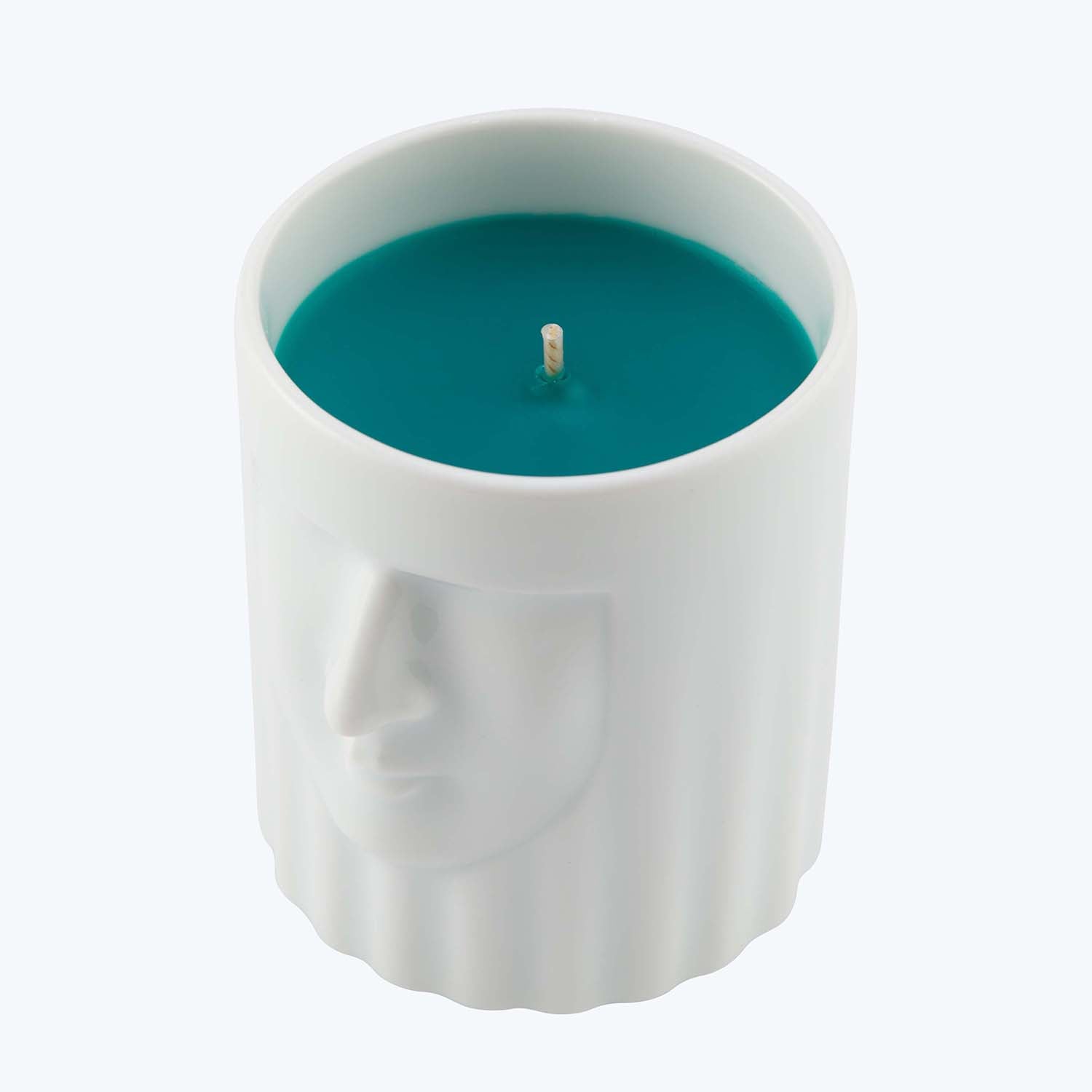 Cylindrical candle with human-like face design in vibrant teal.