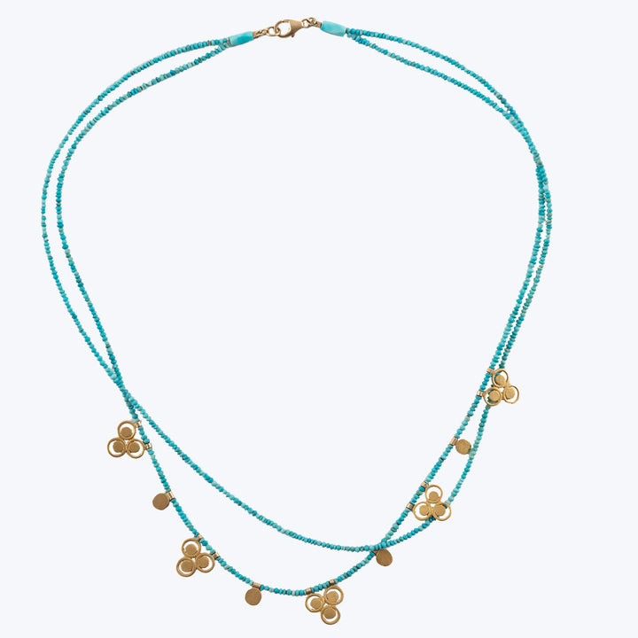 Bohemian style double-stranded turquoise necklace with gold-toned charms.