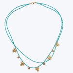Bohemian style double-stranded turquoise necklace with gold-toned charms.