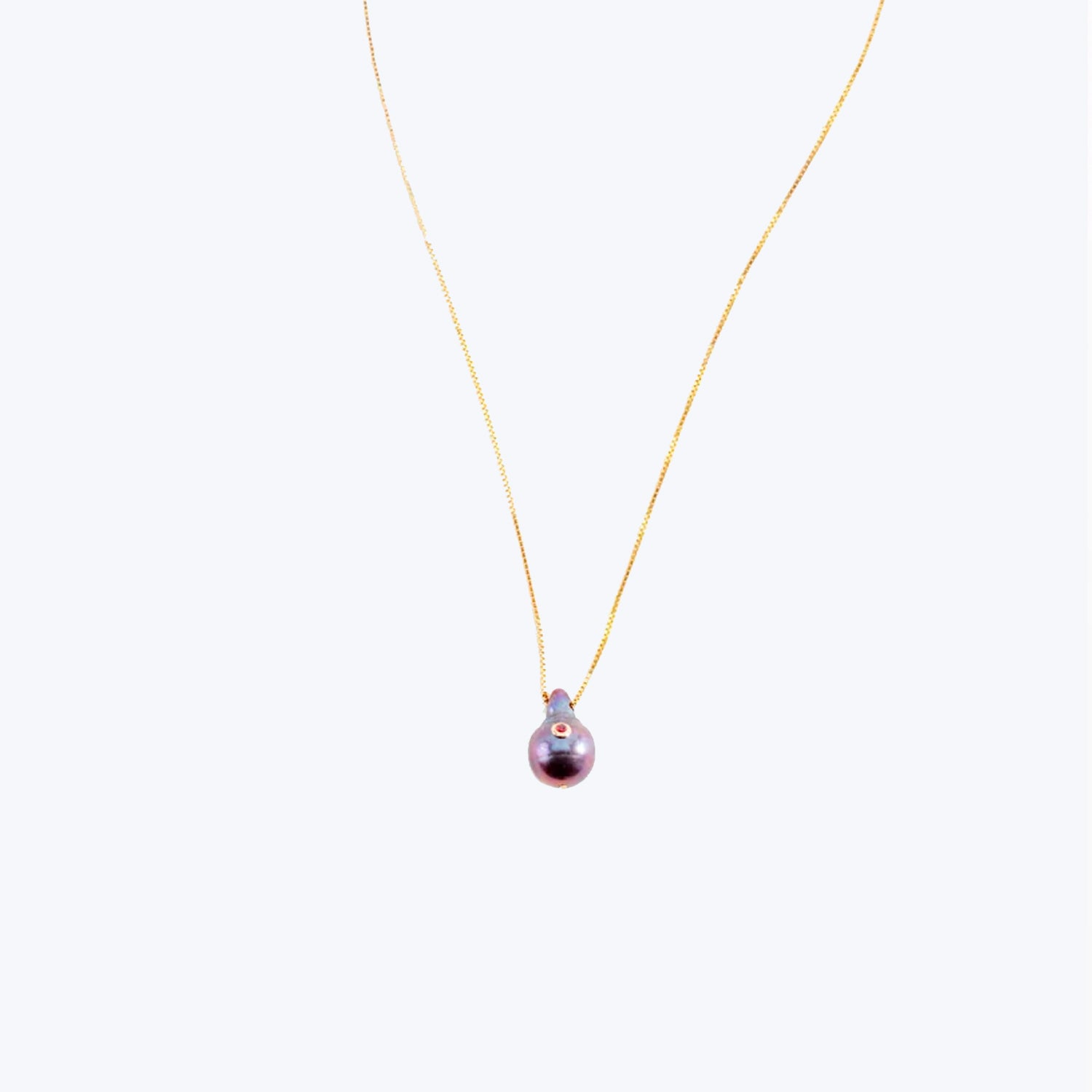 Exquisite gold necklace with iridescent purple pearl pendant shines elegantly.