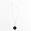 Gold-tone chain necklace with black and white spirograph pendant.
