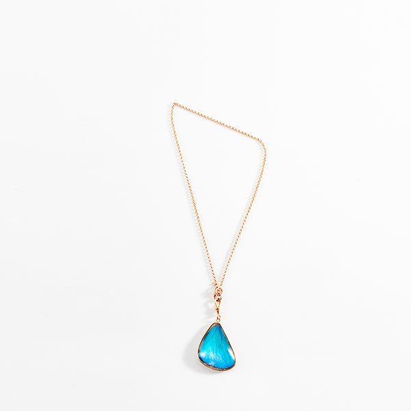 Delicate gold necklace with vibrant blue gemstone pendant hangs gracefully.