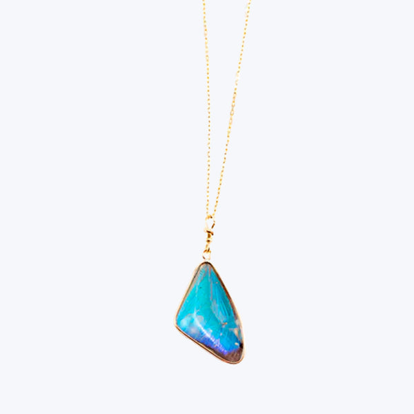 Luminous blue stone pendant on delicate gold-tone chain shines vibrantly.