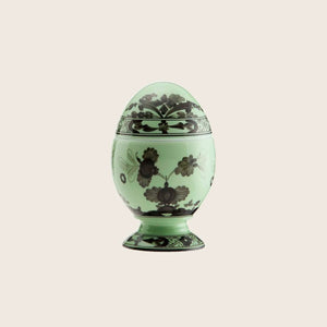 Decorative egg with intricate green floral pattern on matching stand.
