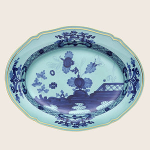 An oval porcelain platter with intricate blue and white Chinese design.