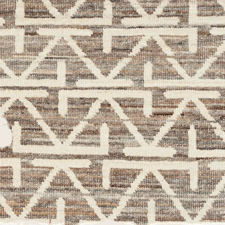 Close-up of a cream geometric patterned fabric or carpet texture.