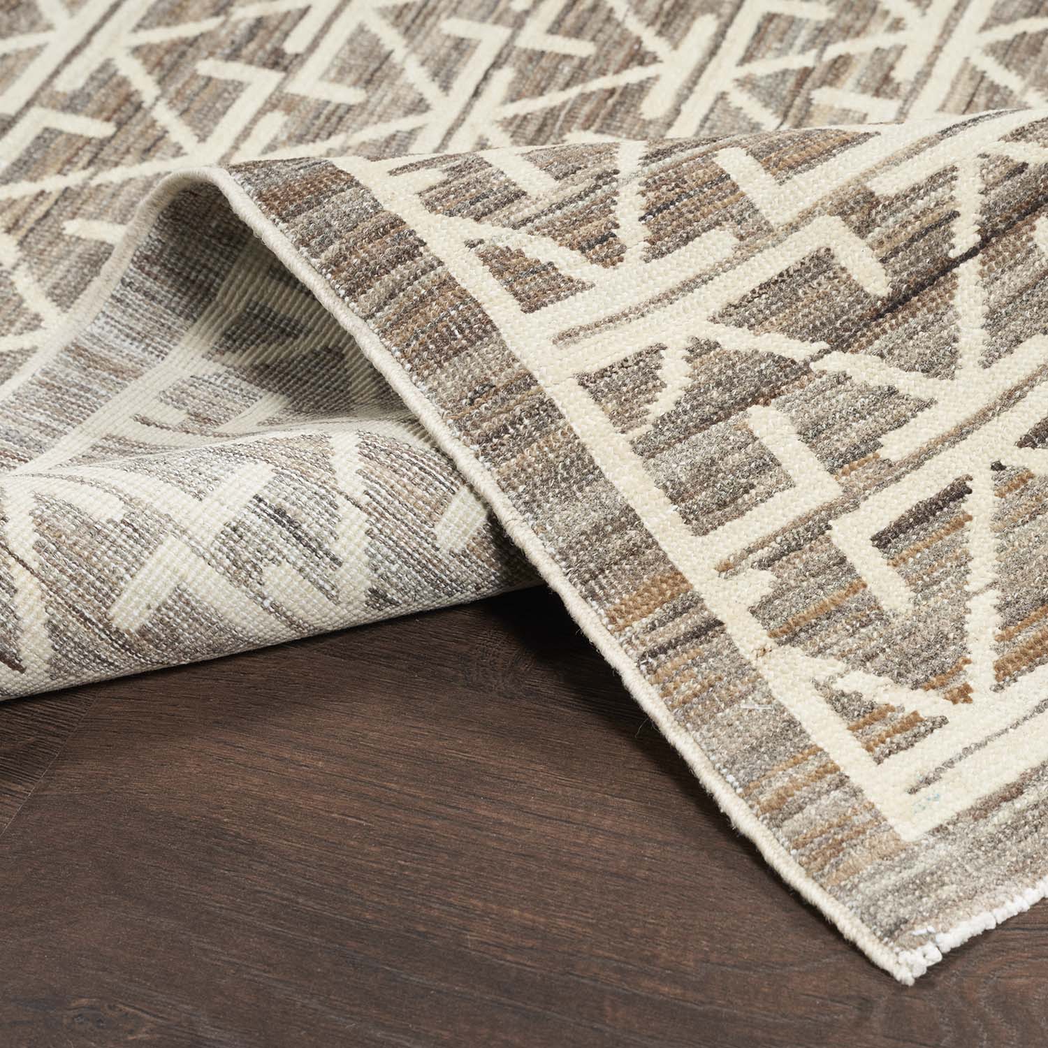 Close-up of modern geometric rug on wooden floor, revealing texture.