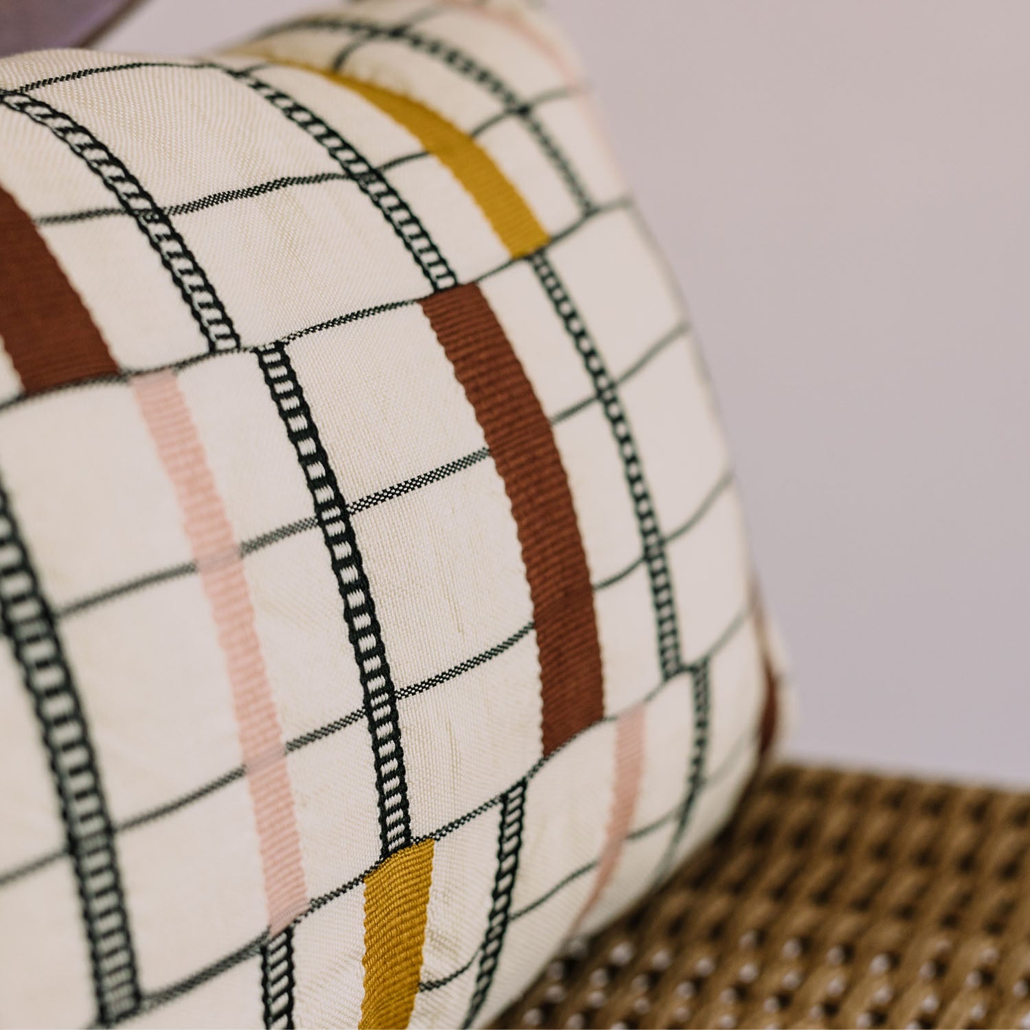 Decorative pillow with geometric pattern in neutral and warm tones.