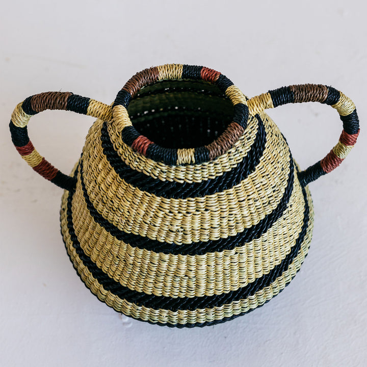 Handcrafted basket with classic pottery design, made with coiled basketry technique and natural fibers. Features two handles and decorative black stripes.