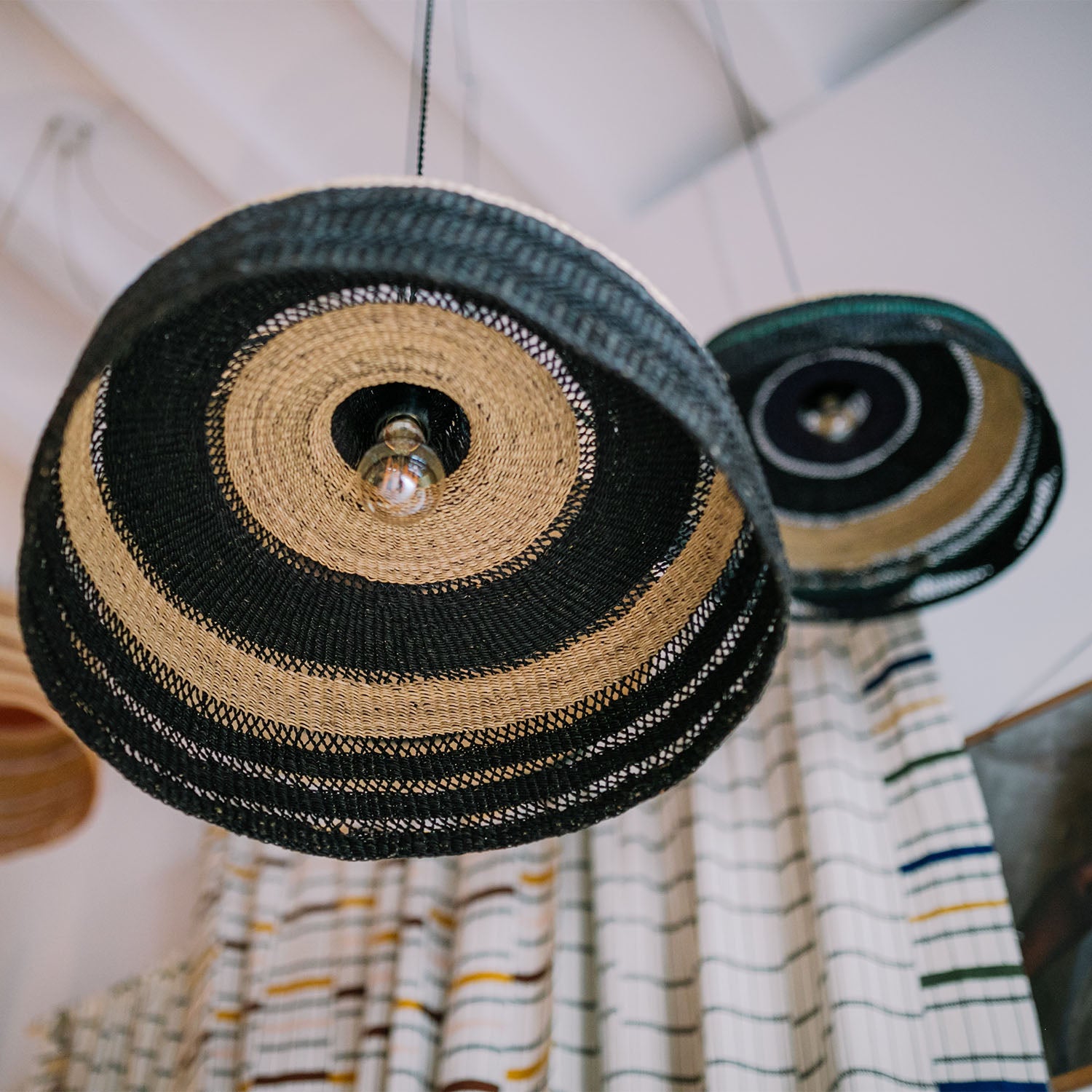 Two oversized woven hat-like light fixtures with concentric patterns.