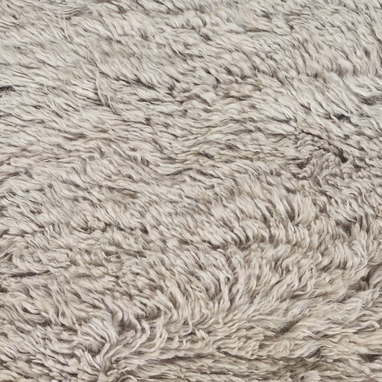 Close-up of shaggy, beige fabric with plush, wavy texture.