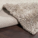 Close-up view of a shaggy rug on dark wooden floor.