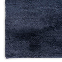 Close-up view of a dense, shaggy dark blue textile surface.