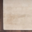 Close-up of shaggy cream rug on wooden floor with texture.