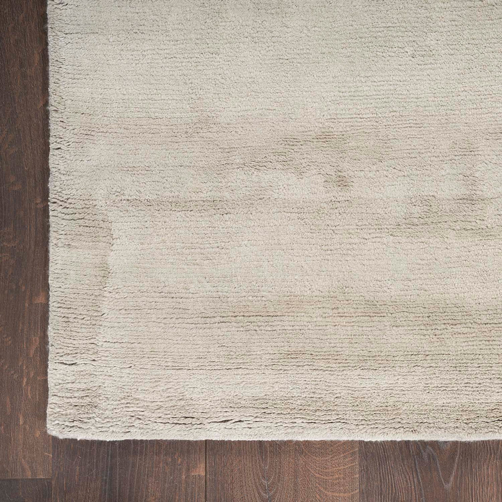 Contrasting textures and colors between wood flooring and frayed rug.