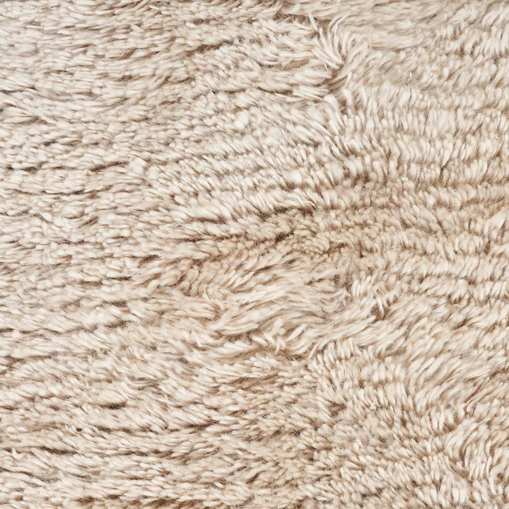Close-up of shaggy beige carpet with thick, plush fibers.