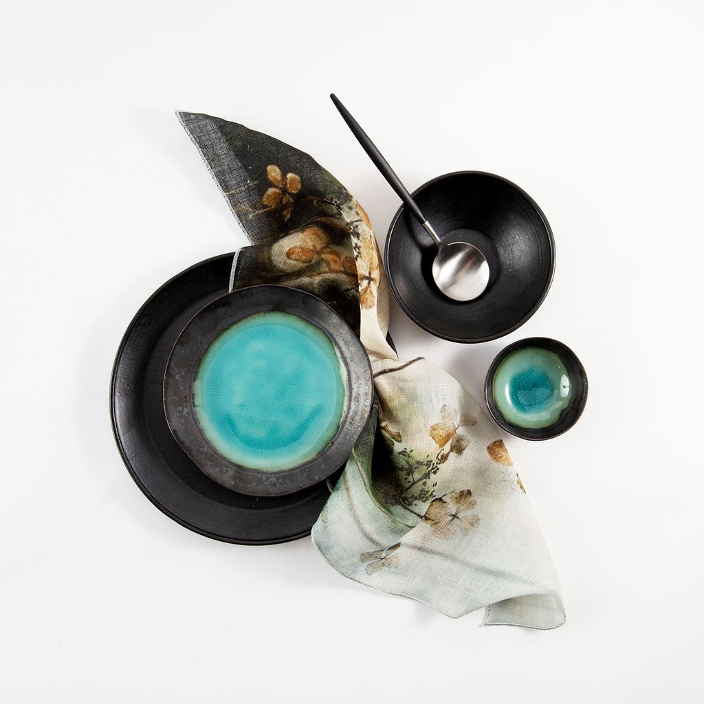 Minimalistic still-life composition featuring black ceramics and blue-hued liquid.