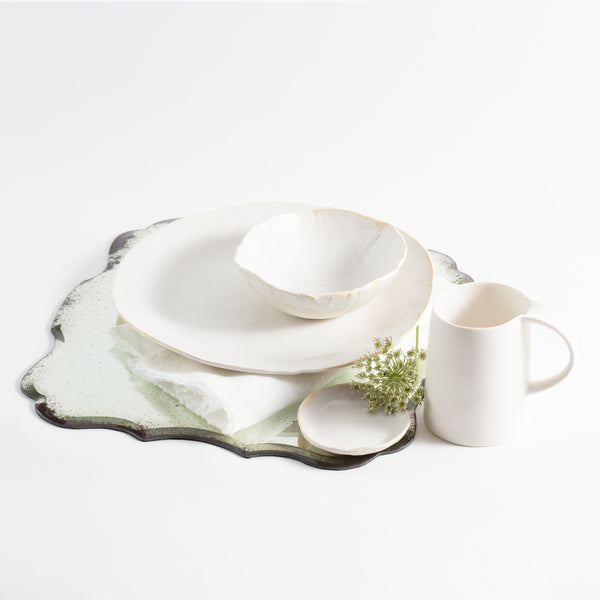 Stylish and textured ceramic tableware arranged with a touch of green.