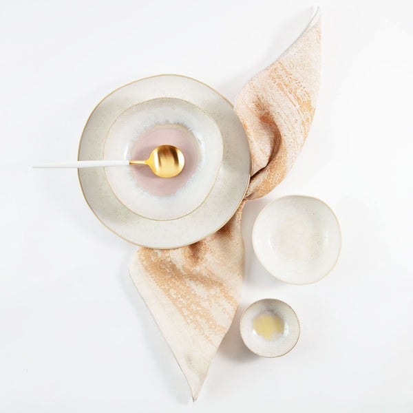 Neatly arranged ceramic tableware with iridescent plate and luxurious spoon.
