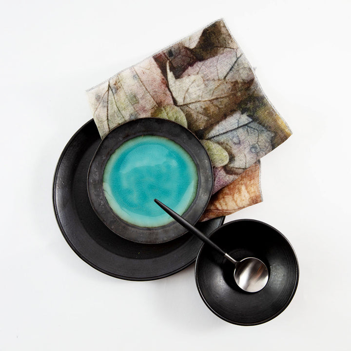 Bowl of blue liquid on rustic plates with metal spoon.