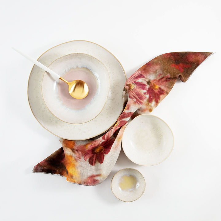 An elegant tabletop arrangement featuring ceramic tableware and a floral textile.