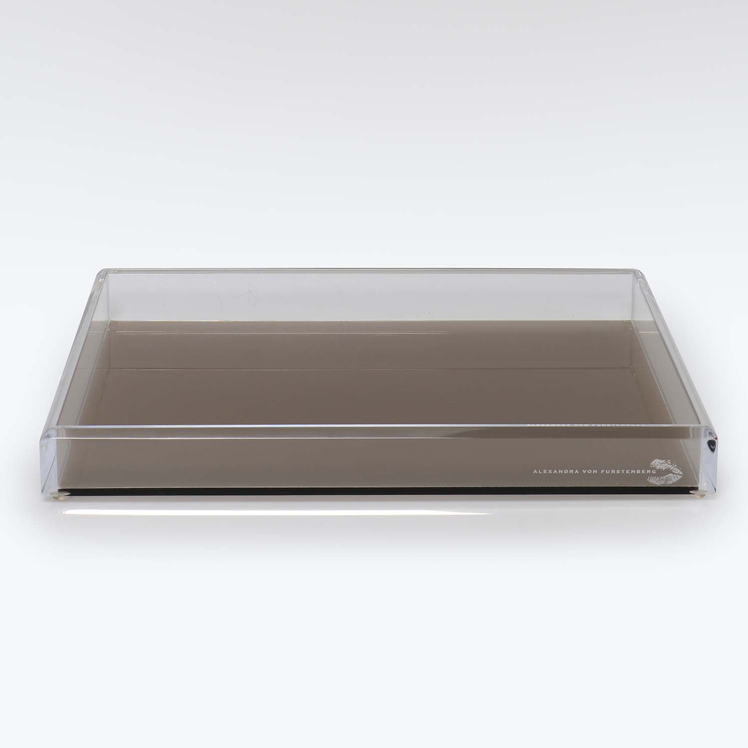 Transparent rectangular tray with a brown base and signature text.