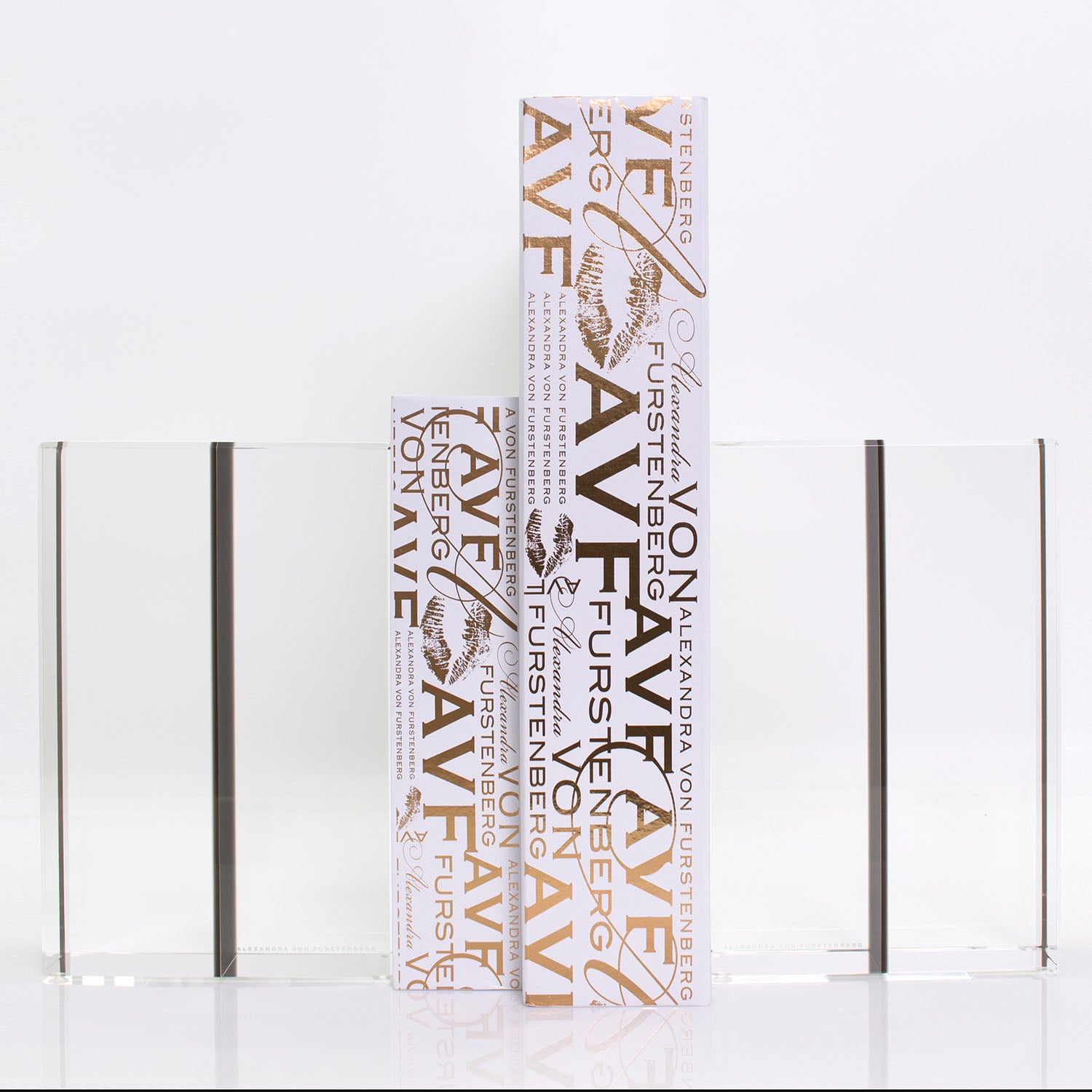 Three elegant nature-themed books displayed between sleek glass bookends.