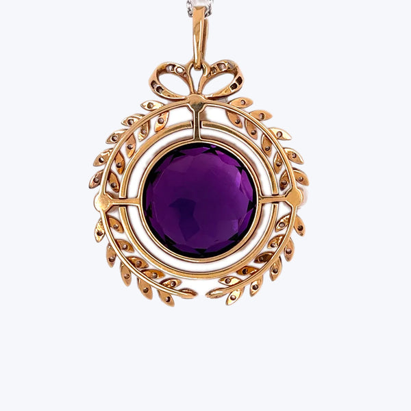 An ornate gold pendant with a large, purple gem centerpiece.