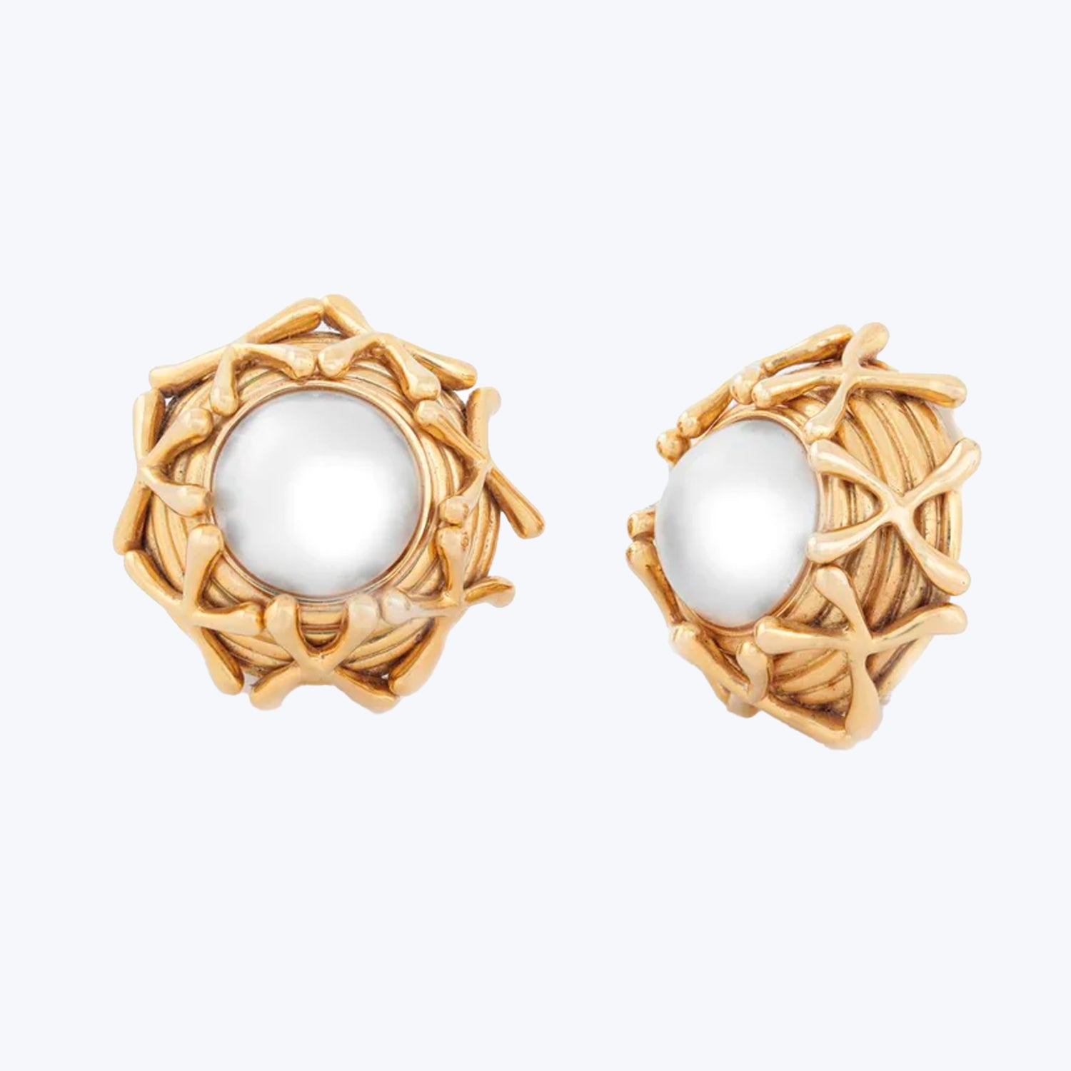 Luxurious gold-toned earrings with white pearl in intricate, organic design.