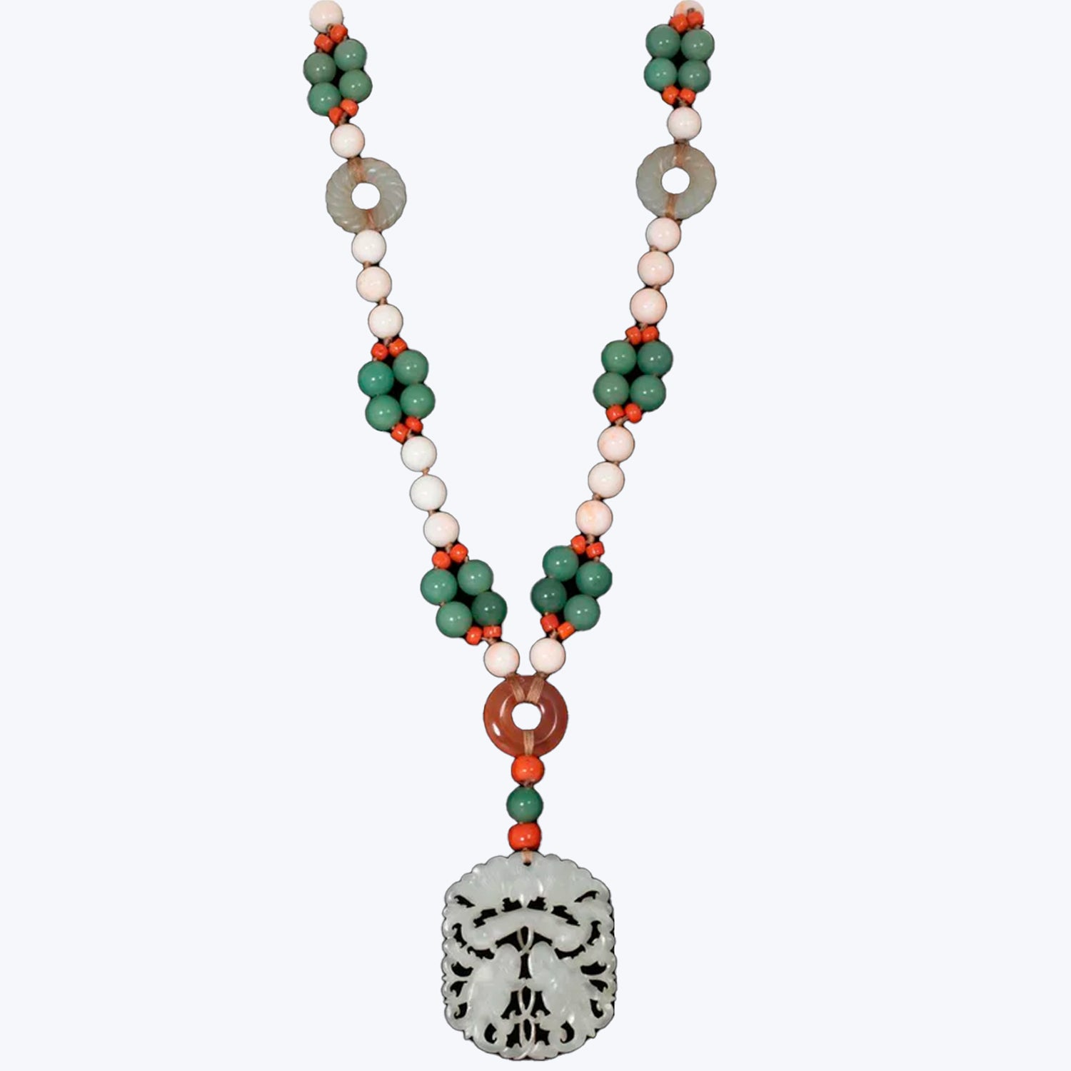 Artisanal necklace features alternating green and red beads leading to skull pendant.