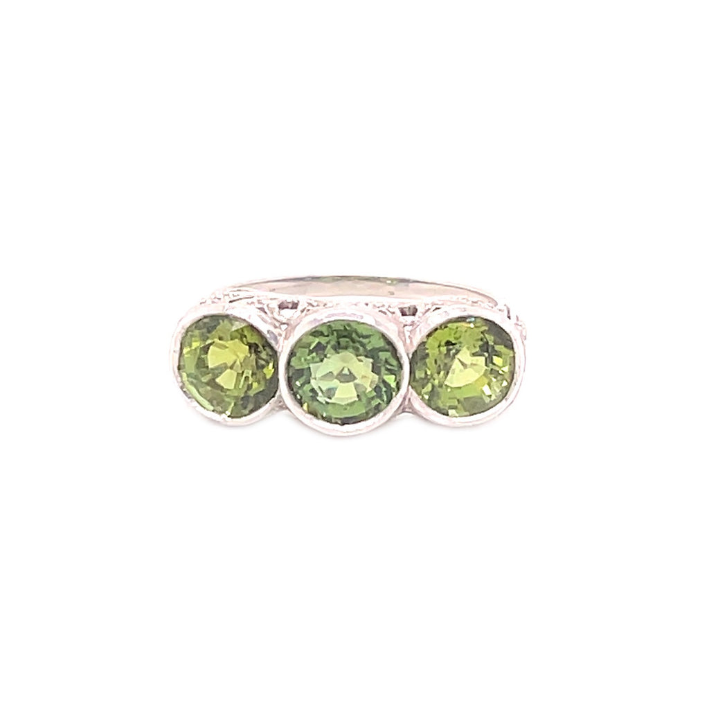 Silver ring with three round-cut green gemstones, highlighting their beauty.