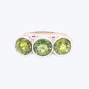 Elegant silver ring with three round-cut green gemstones.