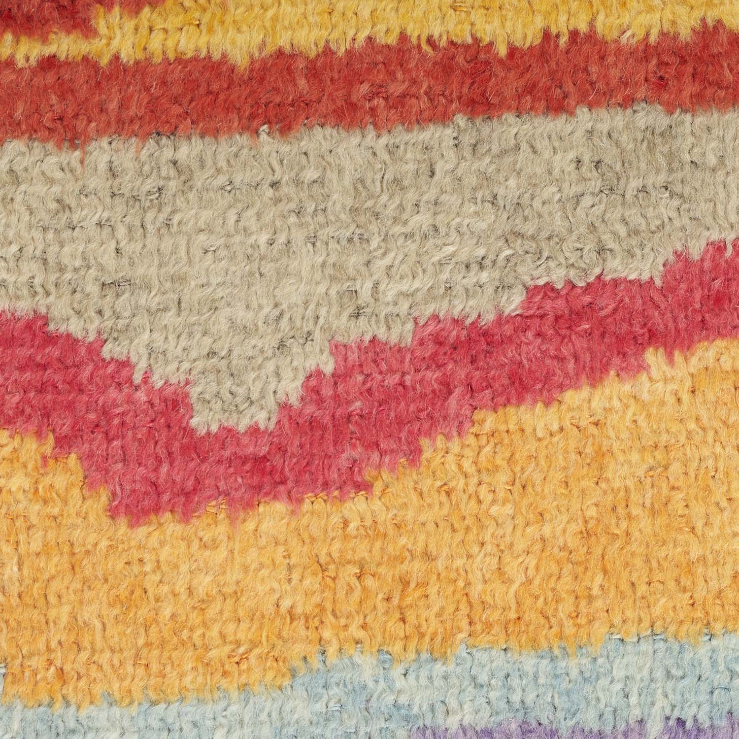 Close-up of multicolored striped rug with fluffy texture and weave pattern.