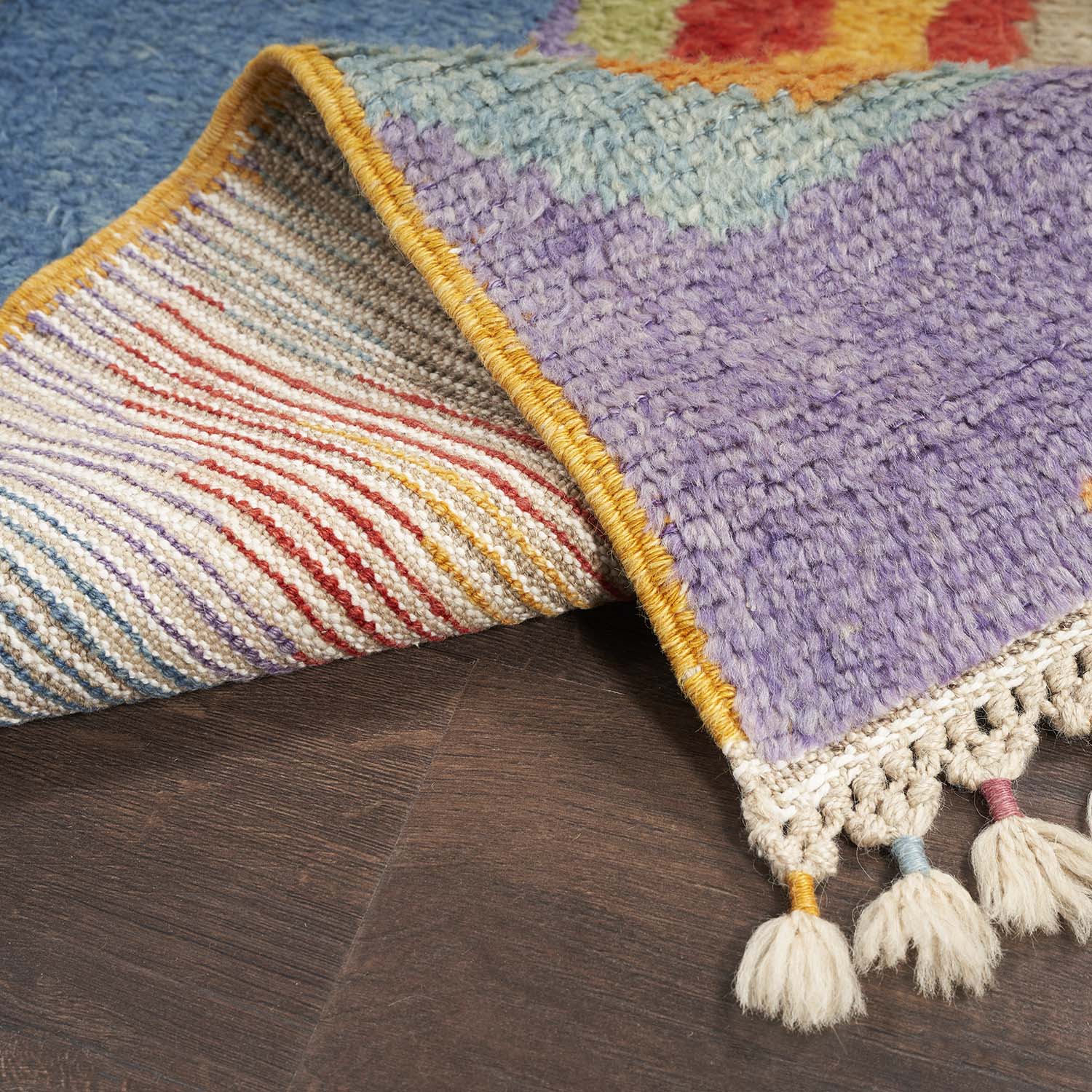 Close-up of vibrant, partially folded rug reveals colorful patterns and fringed tassels.