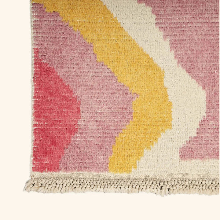 Close-up of a hand-woven rug showcasing abstract, colorful design.