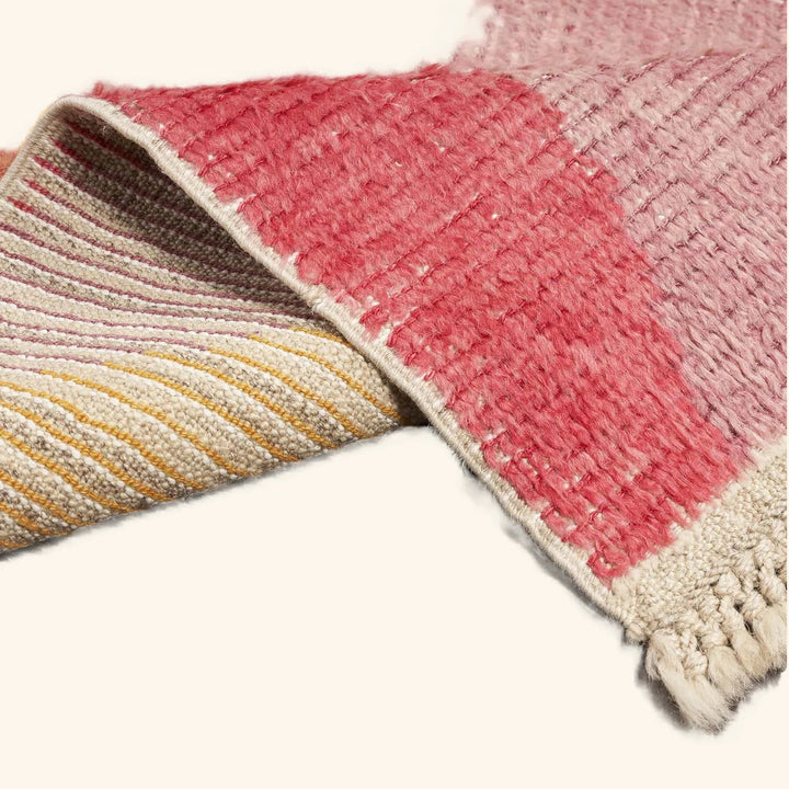 Close-up of a handwoven rug with warm-toned stripes on wood flooring