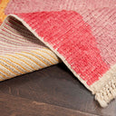 Close-up of a handwoven rug with warm-toned stripes on wood flooring