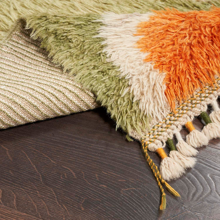 Close-up view of a cozy, gradient textured rug with fringe.