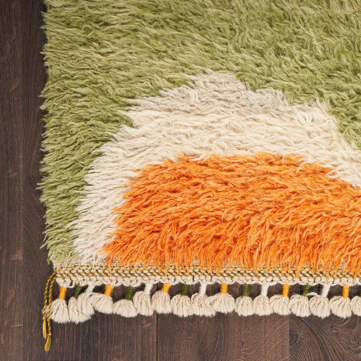 Vibrant gradient rug with fringe on dark hardwood floor.