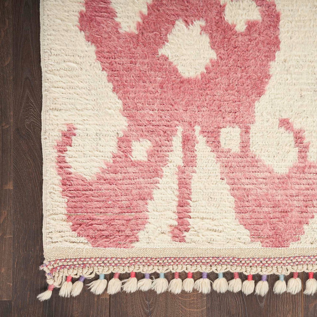 Decorative rug with textured pink and white abstract pattern on wood floor.