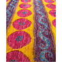 Colorful textile with pink ovals, blue vines, and vibrant patterns.