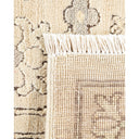 Close-up of a cream and beige woven rug with fringed border.