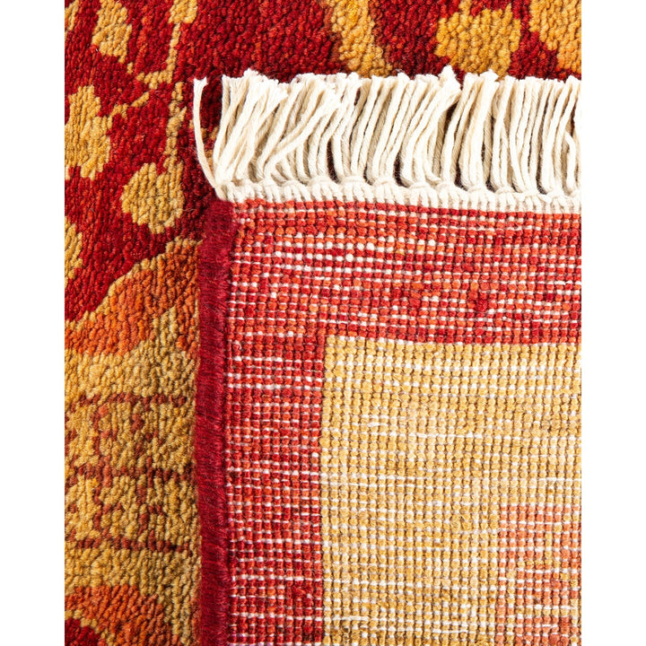 Close-up of a vibrant, intricate handwoven rug with fringe detail.