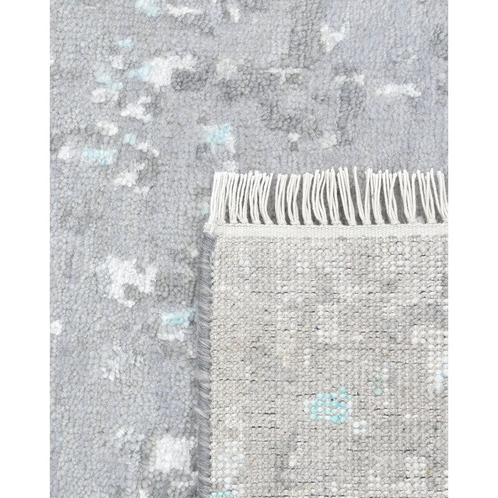 Textured grey rug with subtle blue pattern and artisanal fringe