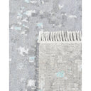 Textured grey rug with subtle blue pattern and artisanal fringe