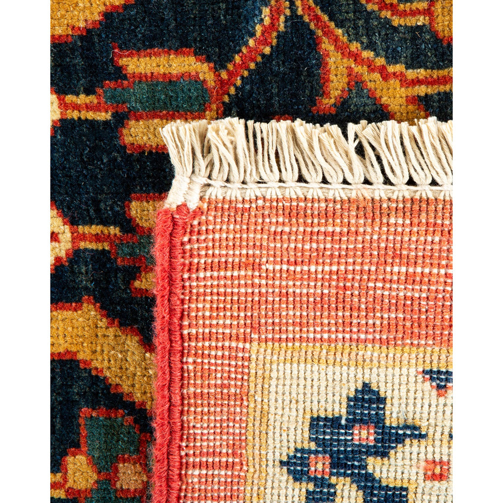 Close-up of a traditional hand-woven rug with intricate geometric patterns and fringe.