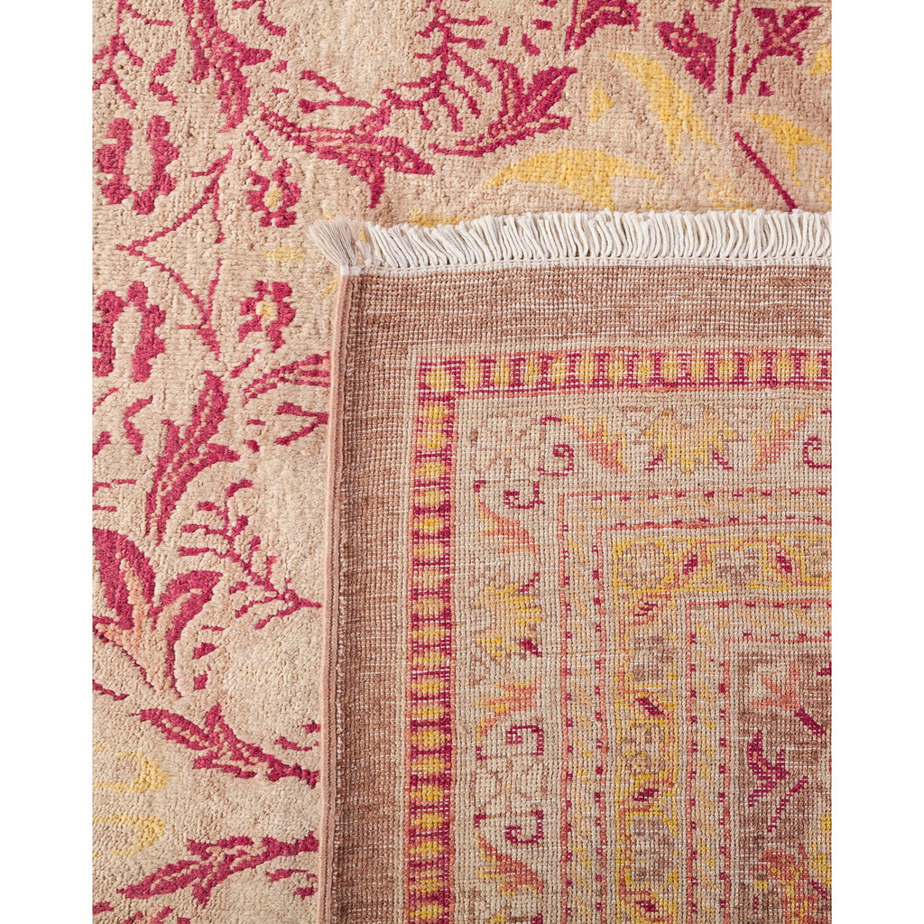 Close-up view of an ornate, handcrafted Oriental rug with floral and geometric designs in shades of beige, red, pink, and yellow, featuring intricate motifs and white fringe.