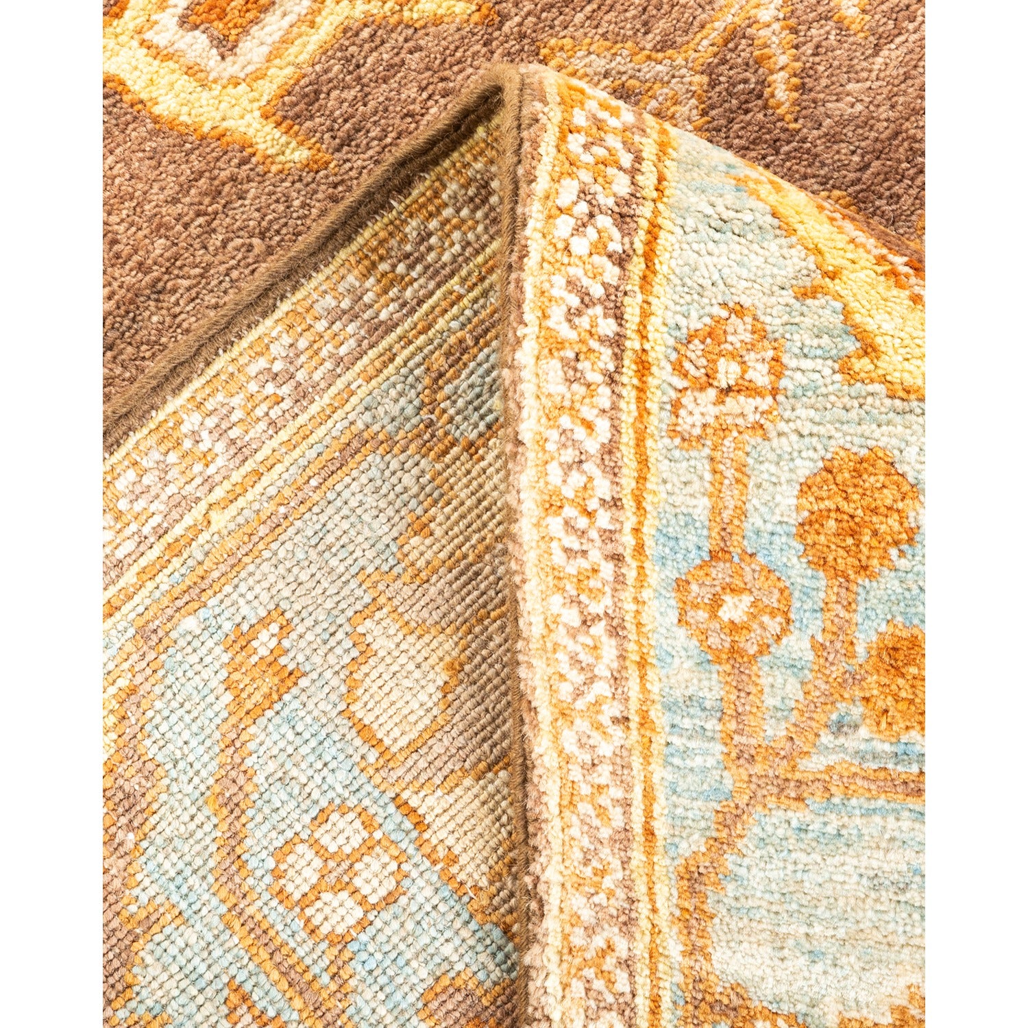 Close-up of folded rug with floral pattern, earthy colors and plush texture.