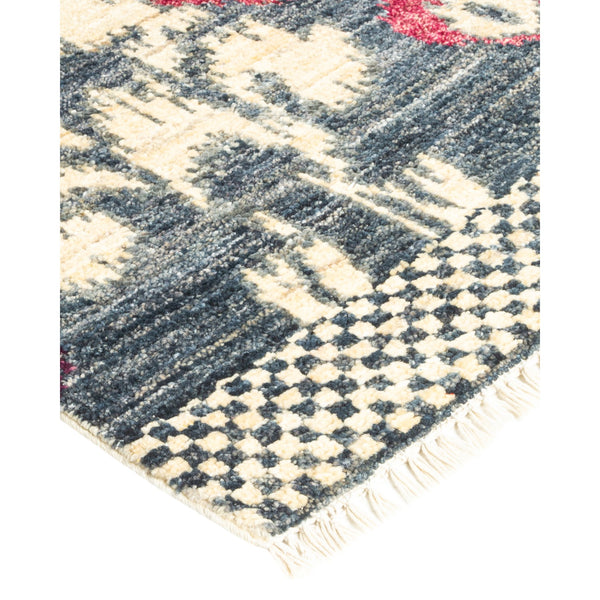 Close-up of a patterned rug with diamond shapes and fringed ends.