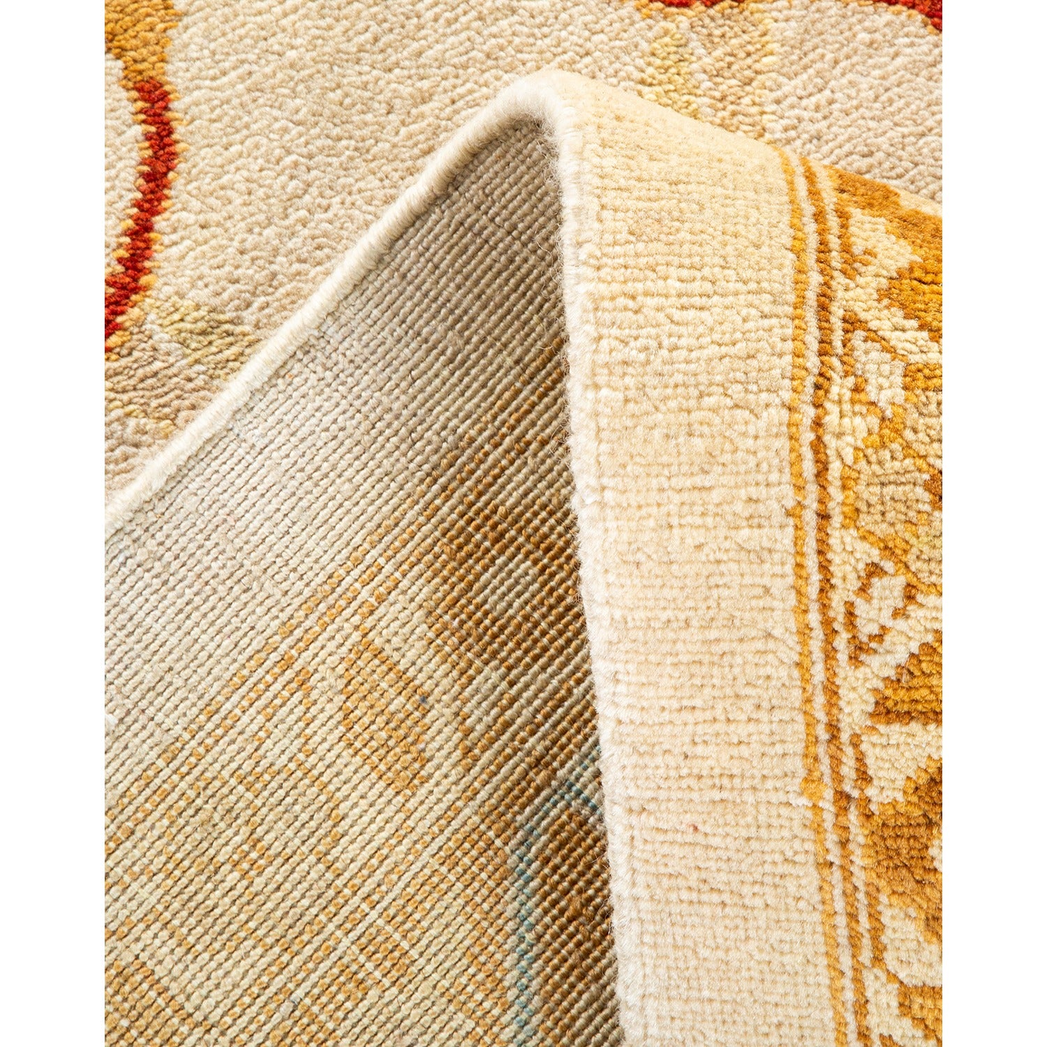 Close-up of a plush rug with folded back segments revealing intricate design and striped backing.
